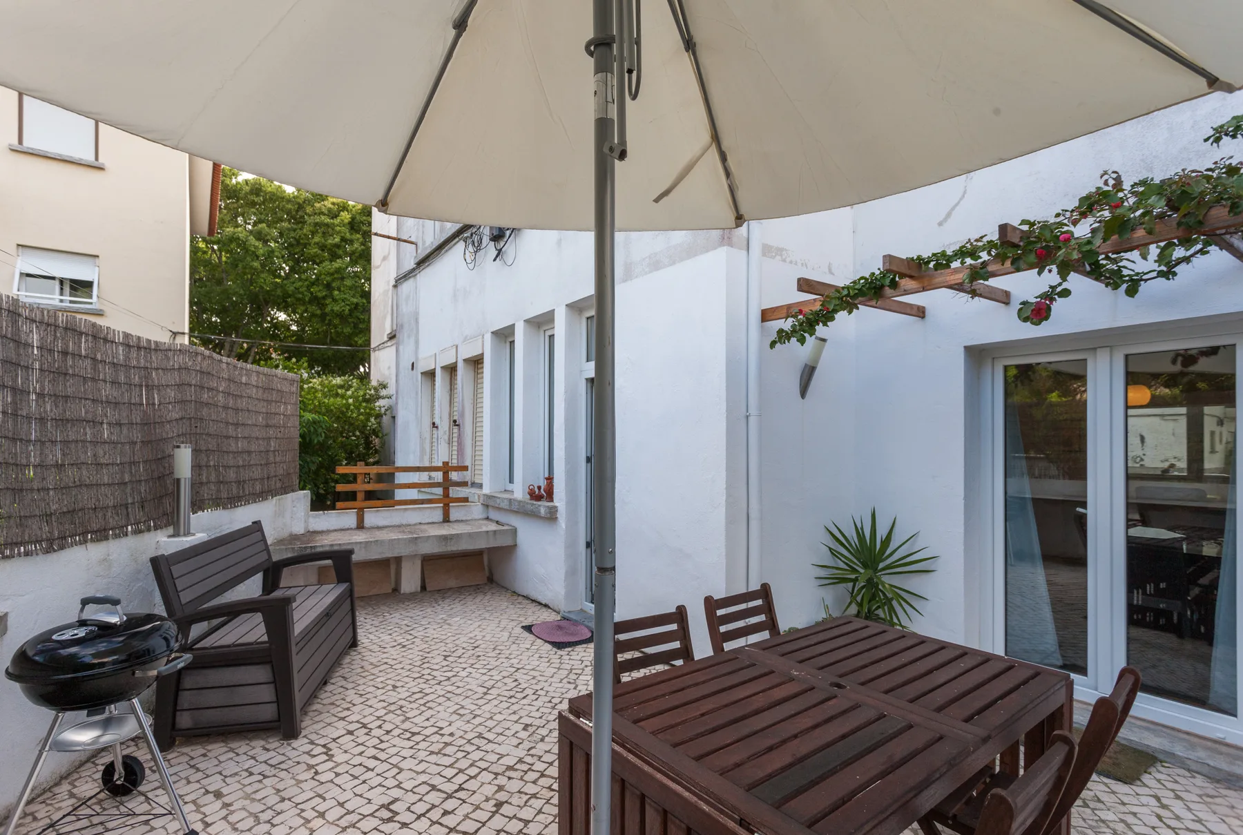 Una terraza pavimentada con asientos al aire libre y una sombrilla grande.