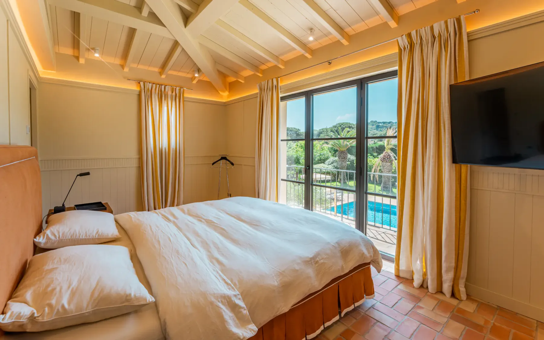 Dormitorio con cama doble y puertas correderas de cristal que dan a una terraza con vistas a la piscina