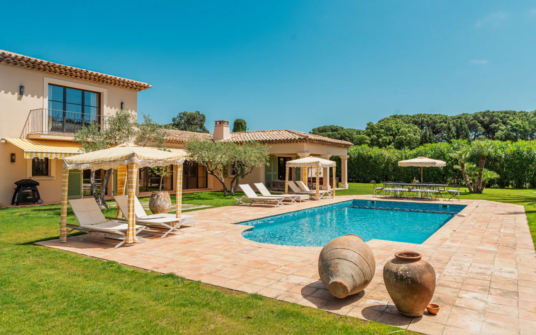 Una piscina está junto a un patio embaldosado y asientos al aire libre.
