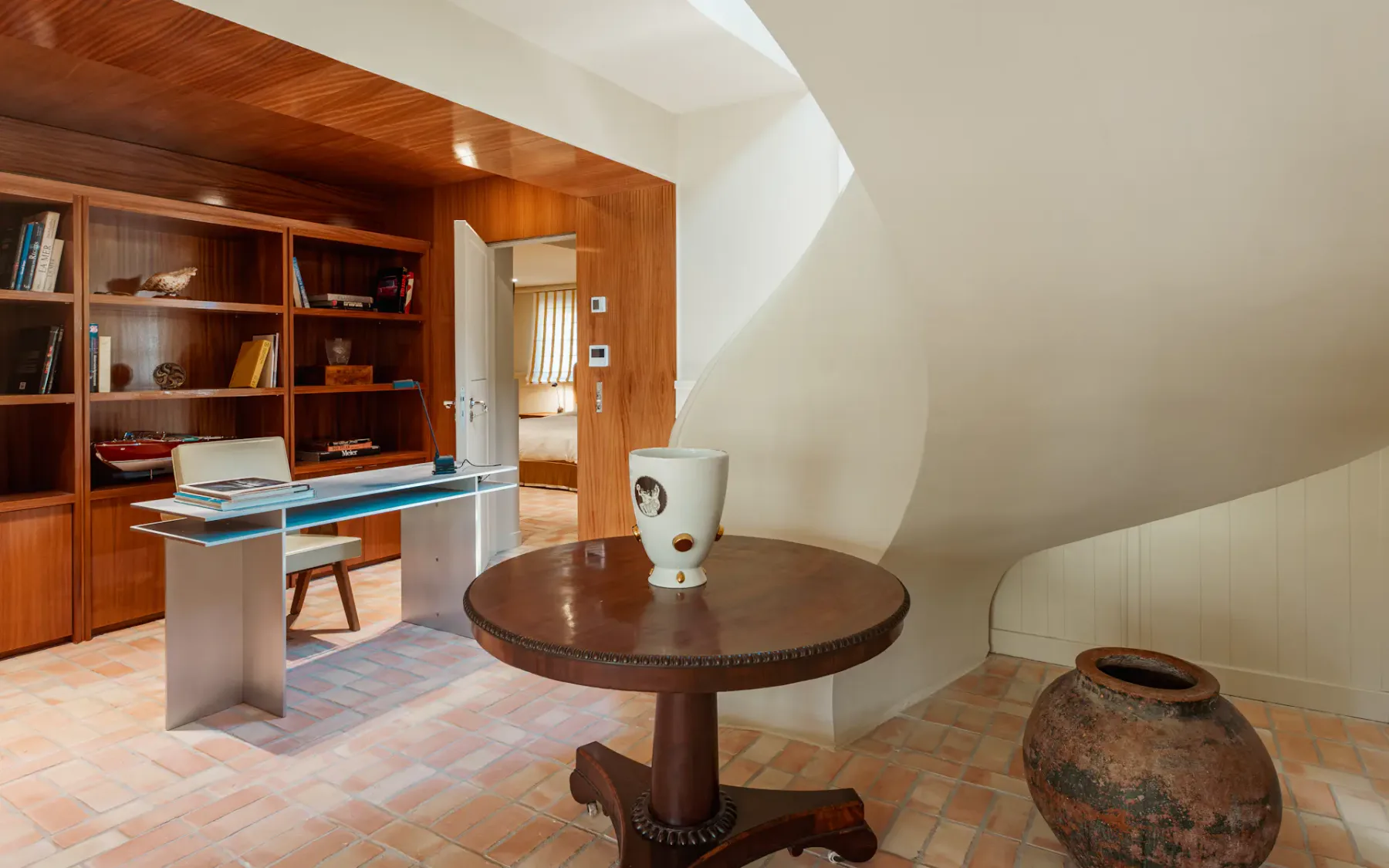 Zona de estudio con un escritorio de vidrio junto a estanterías de madera empotradas.