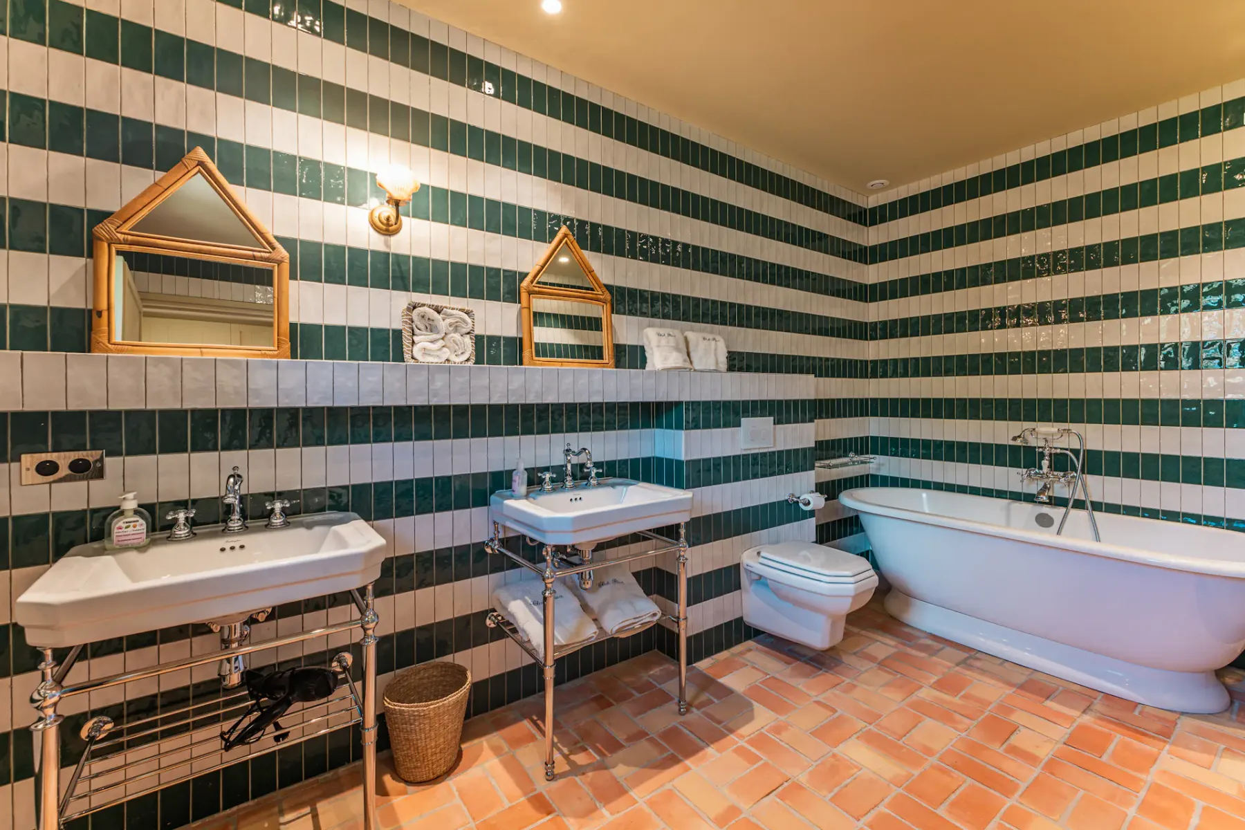 Baño grande con azulejos verdes y blancos, lavabo, espejo y bañera