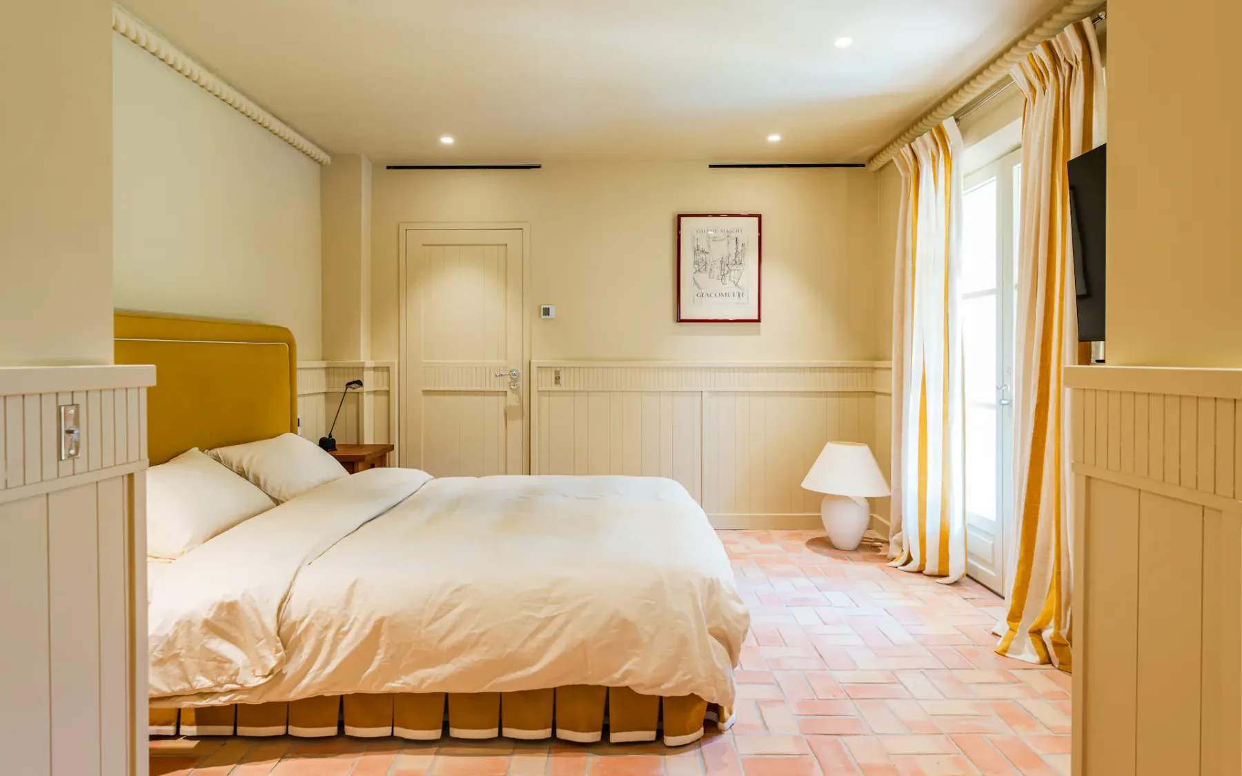 Dormitorio con cama doble y ventanas altas con cortinas
