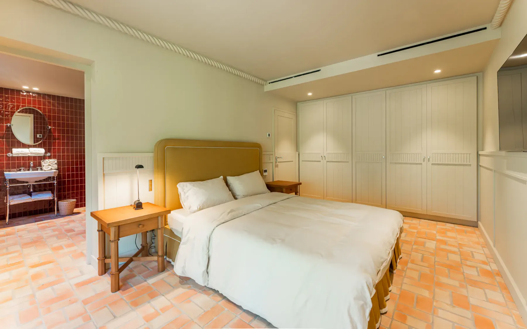 Un dormitorio con una cama junto a una entrada al baño y armarios empotrados.