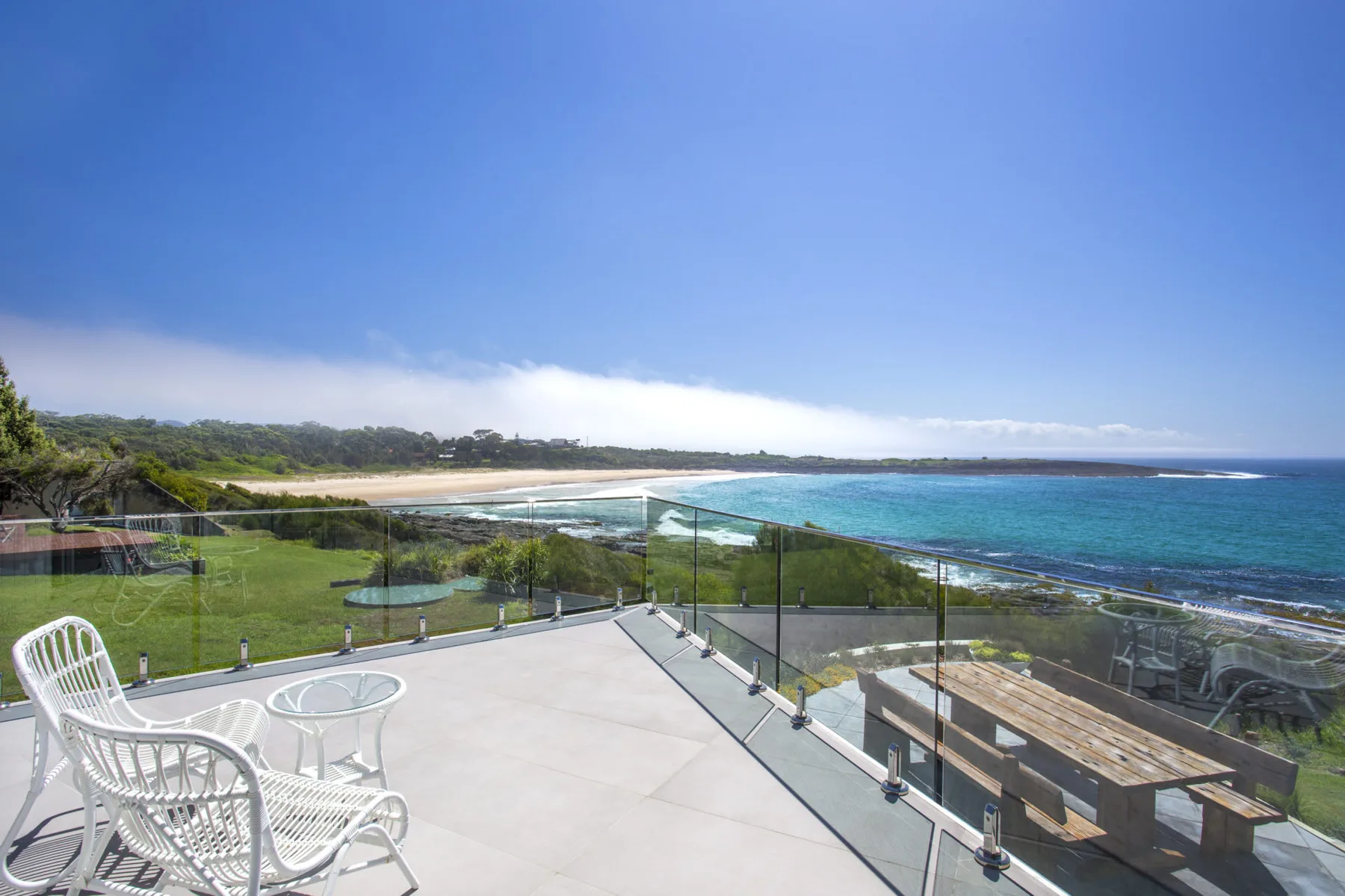 Una terraza junto al mar da a una playa de arena y al océano azul.