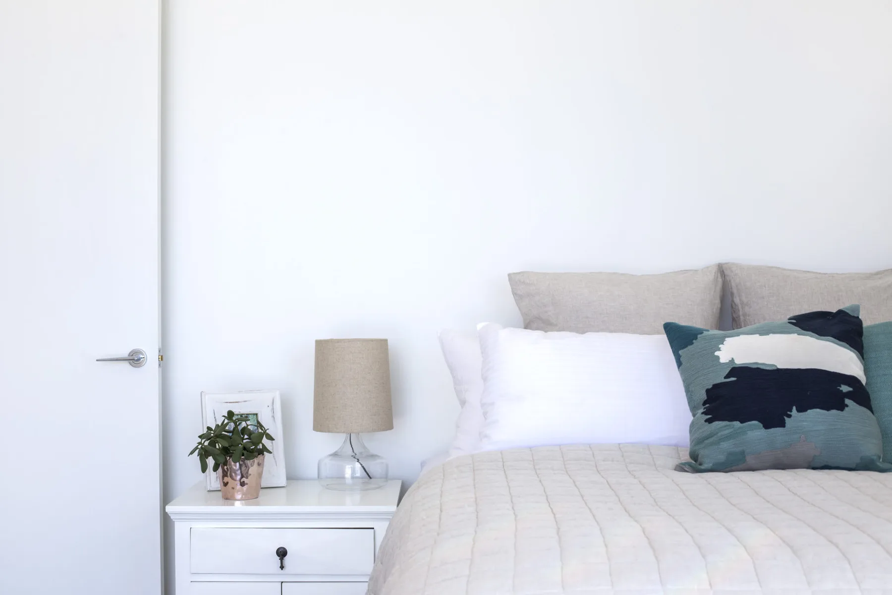Un dormitorio con una cama tendida y una mesita de noche.