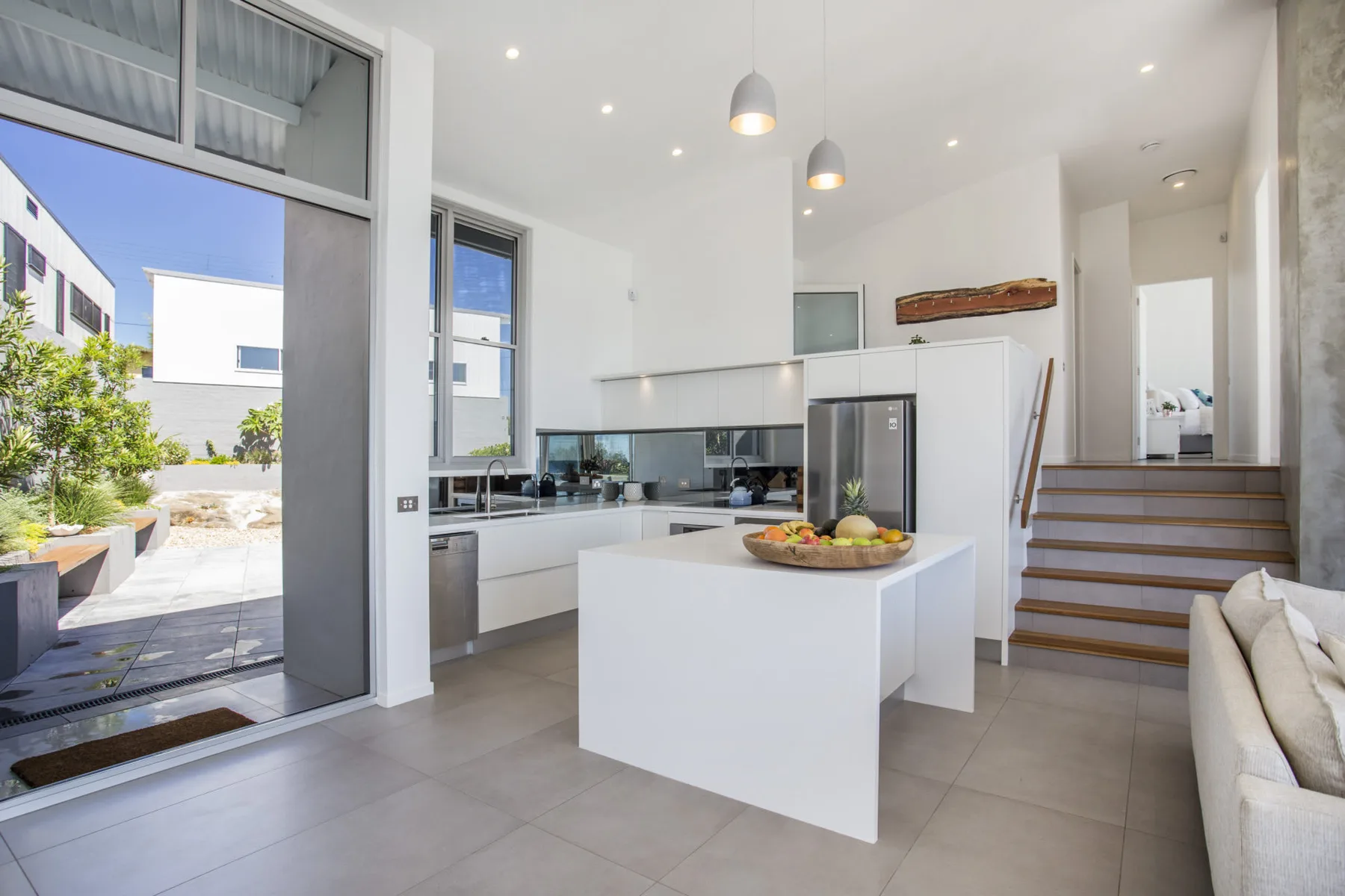 Una cocina luminosa con una isla central y una puerta de vidrio que da a un patio.
