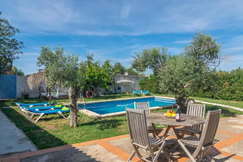 An outdoor swimming pool sits beside a patio table and seating.