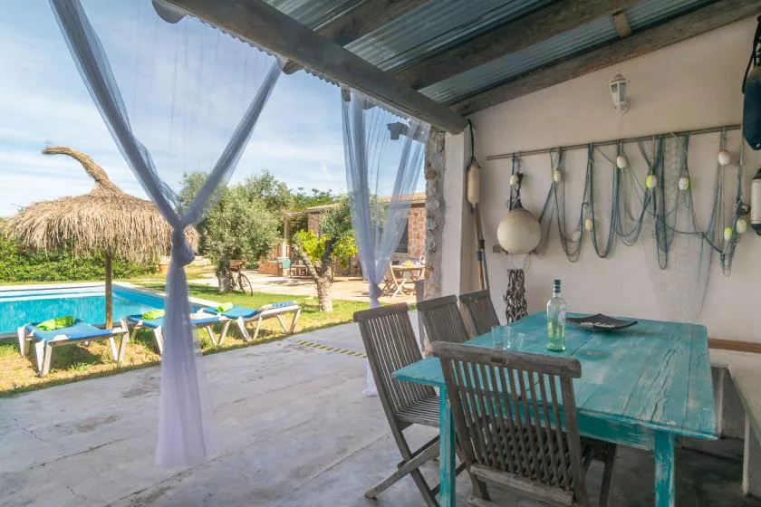 A covered patio dining area opens onto a pool and landscaped garden.