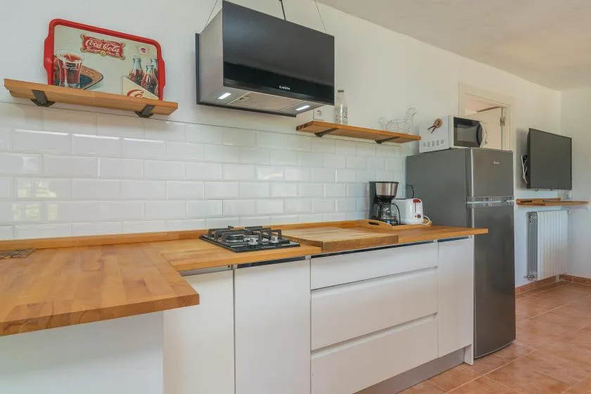 A kitchen with wooden countertops, white cabinets, and stainless steel appliances.