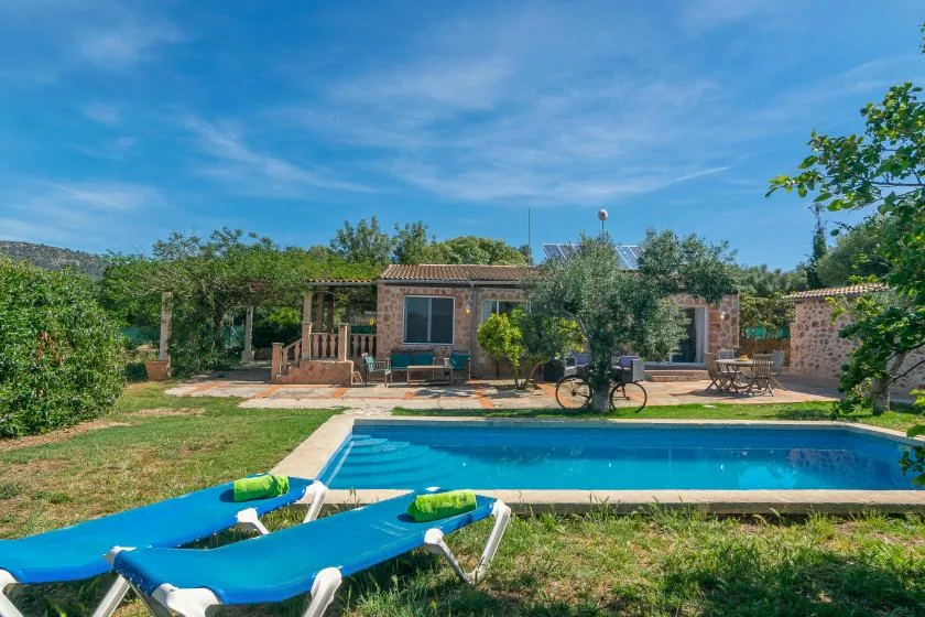 A backyard pool sits in front of a single-story house, with lounge chairs nearby.