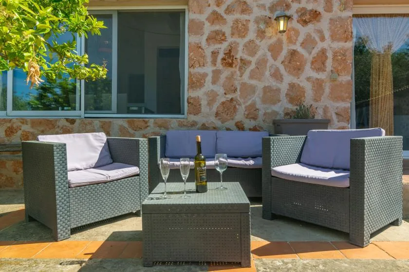 An outdoor patio seating area with woven chairs and a low table.
