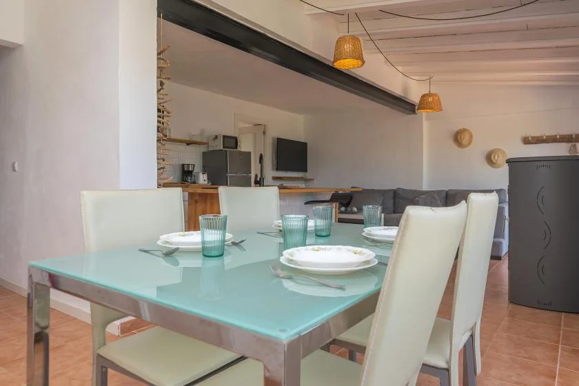 A dining area with a glass table set with plates and drinking glasses.