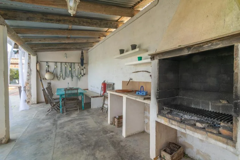 A covered outdoor cooking area with a large built-in grill and a dining table.