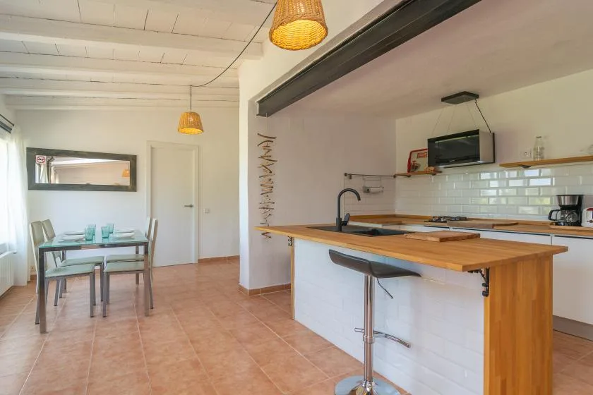 An open kitchen with a wooden counter and a dining table by the window.