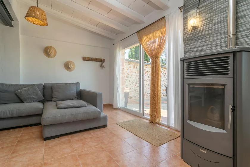A living room with a gray sectional, sliding glass doors, and a freestanding stove.