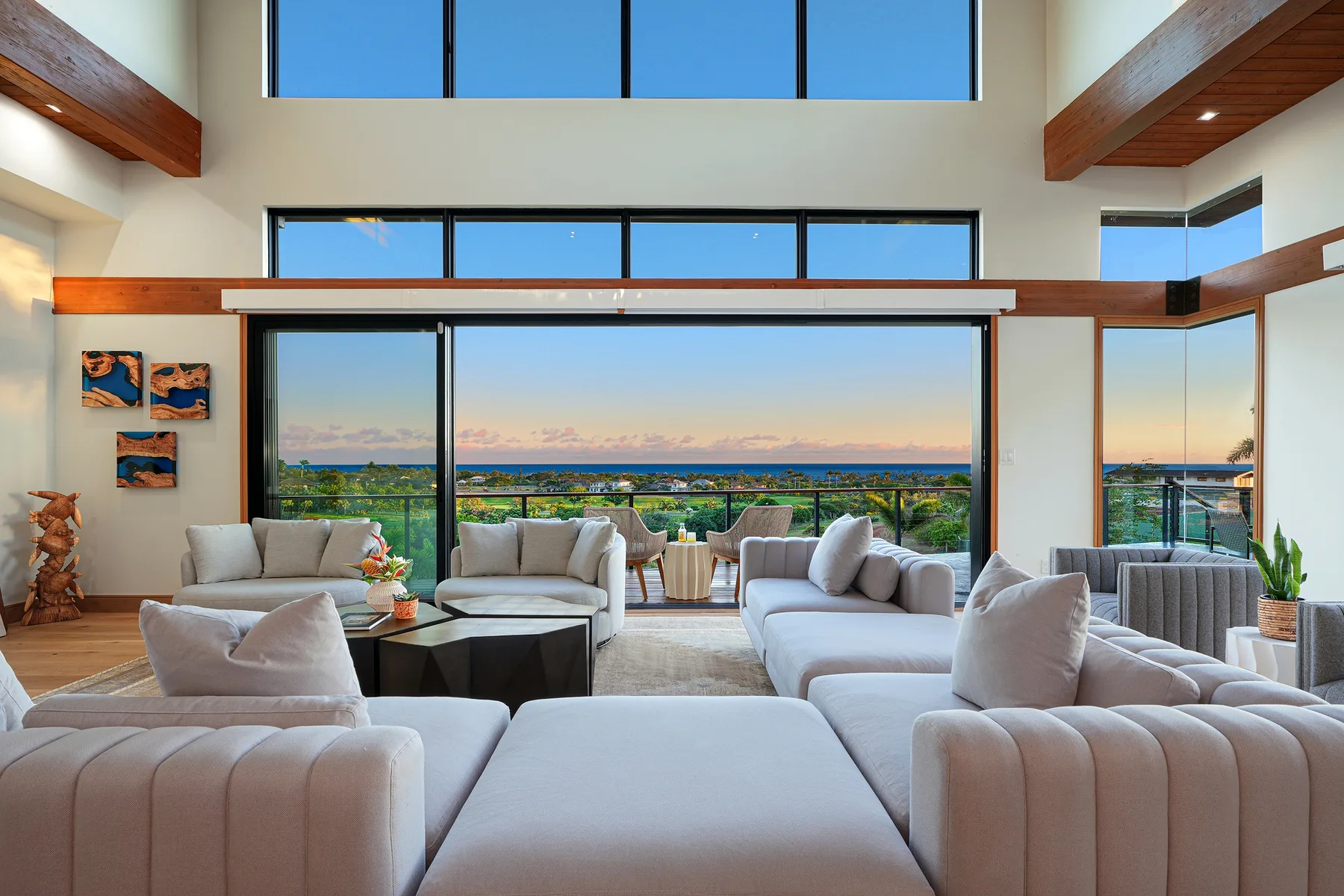 A spacious living room with seating arranged before wide windows overlooking the landscape.