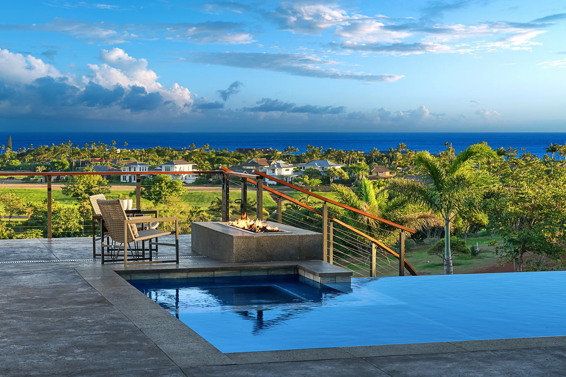 An outdoor pool overlooks a landscaped garden and the ocean.