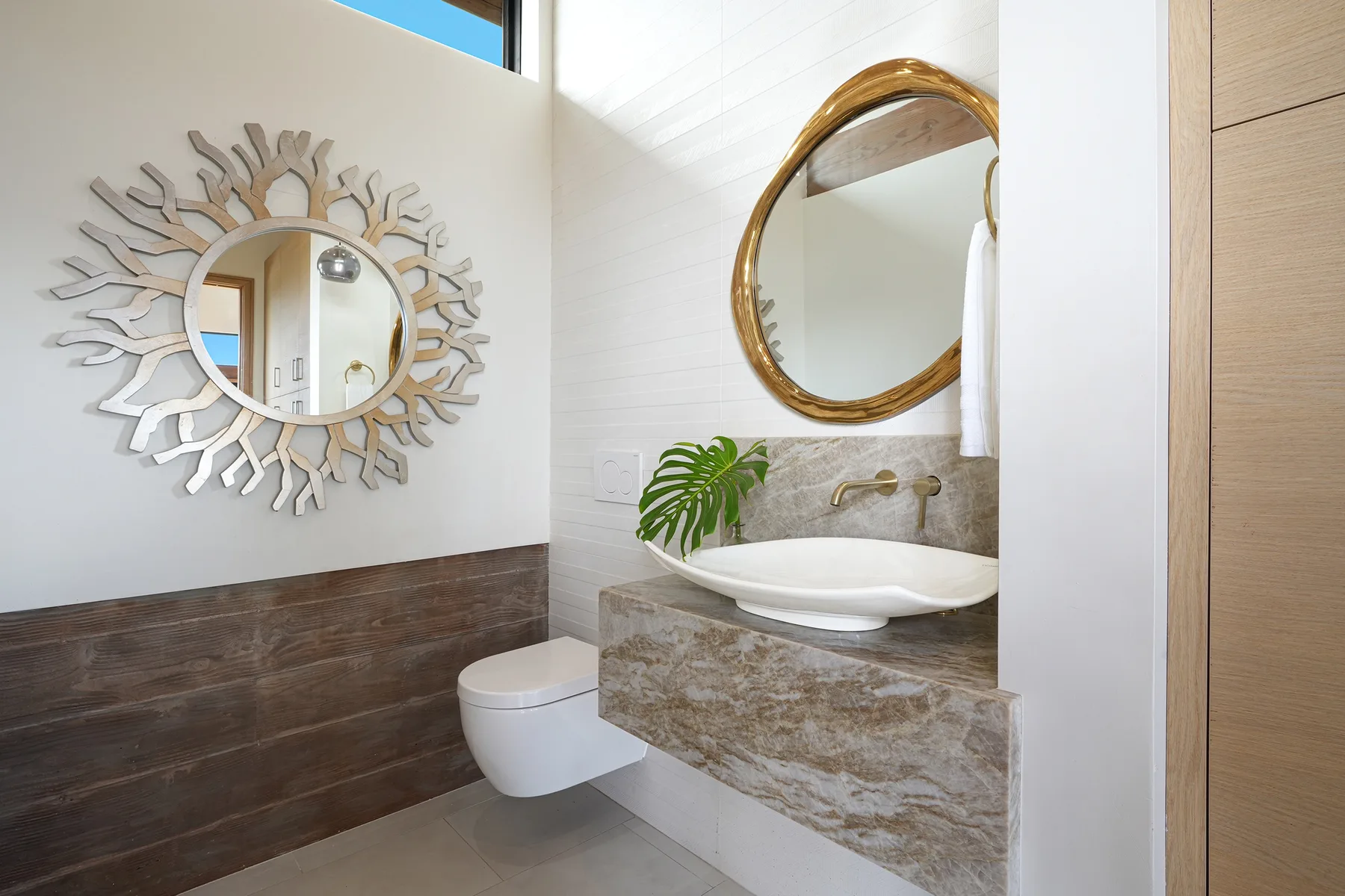 A bright bathroom with a floating vanity, vessel sink, and decorative mirrors.