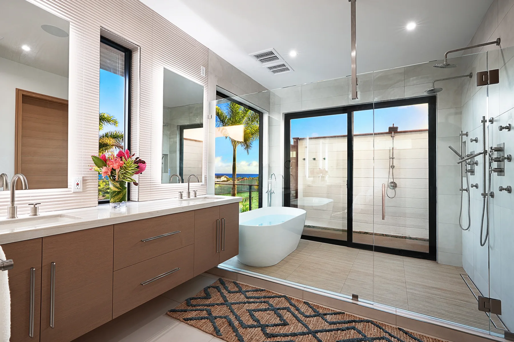 A bright bathroom with a freestanding tub, vanity, and glass shower.