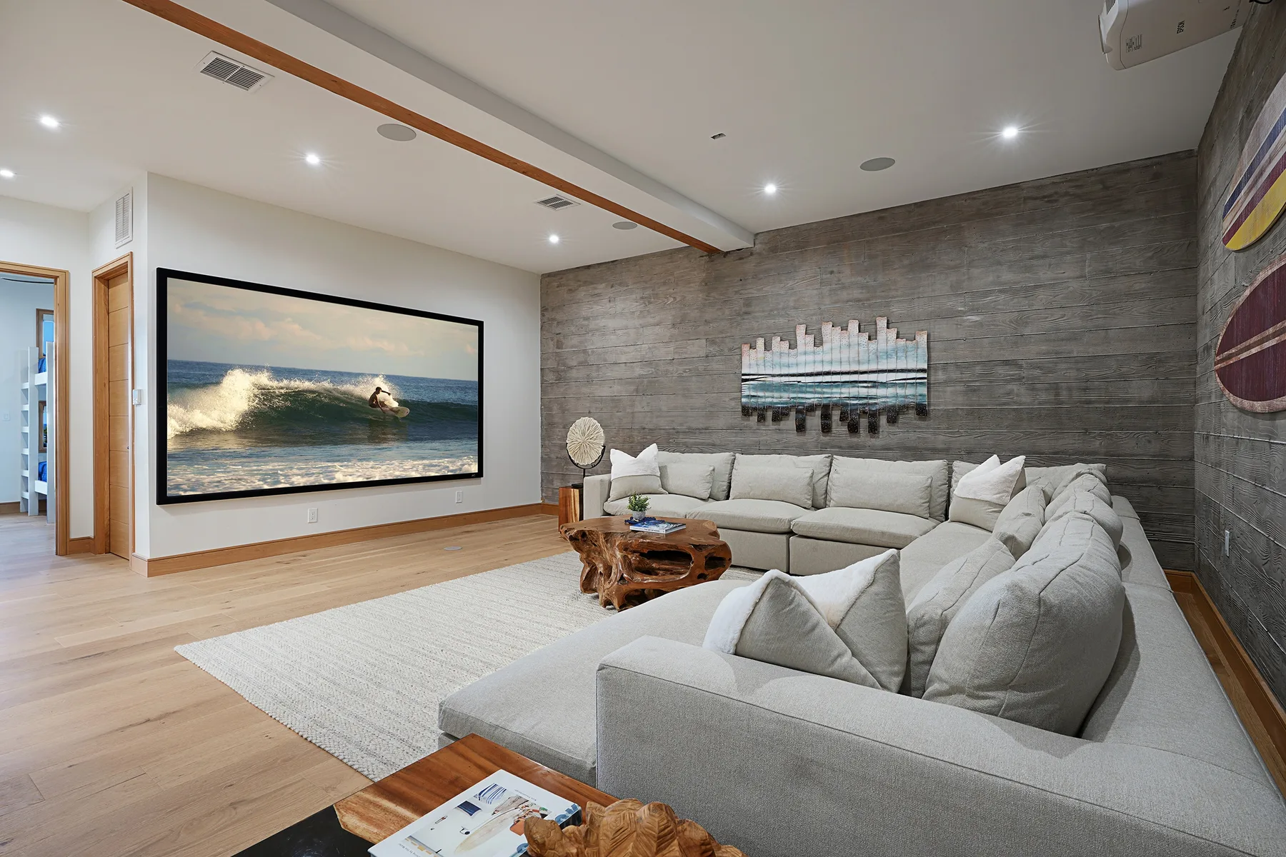 A living room with sectional seating, a large screen, and wall art.