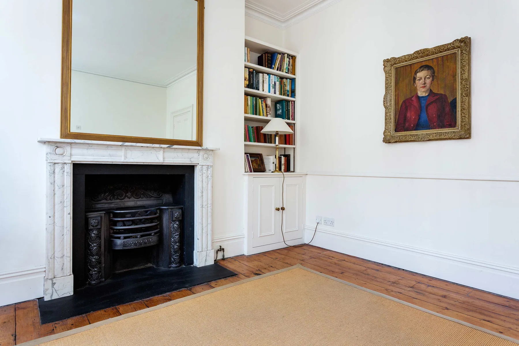 A bright living room with a fireplace, built-in shelves, and a framed portrait.