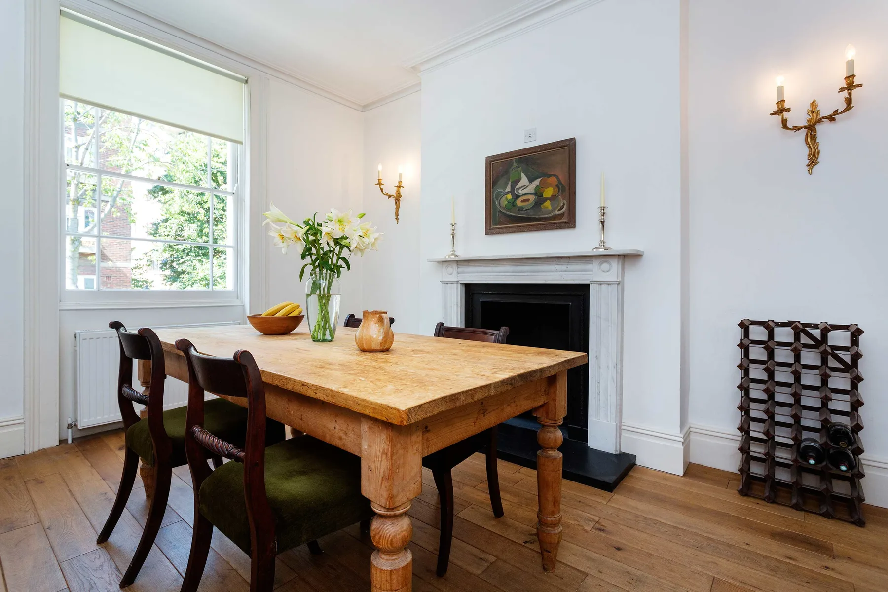 A dining room with a wooden table, chairs, and a fireplace.