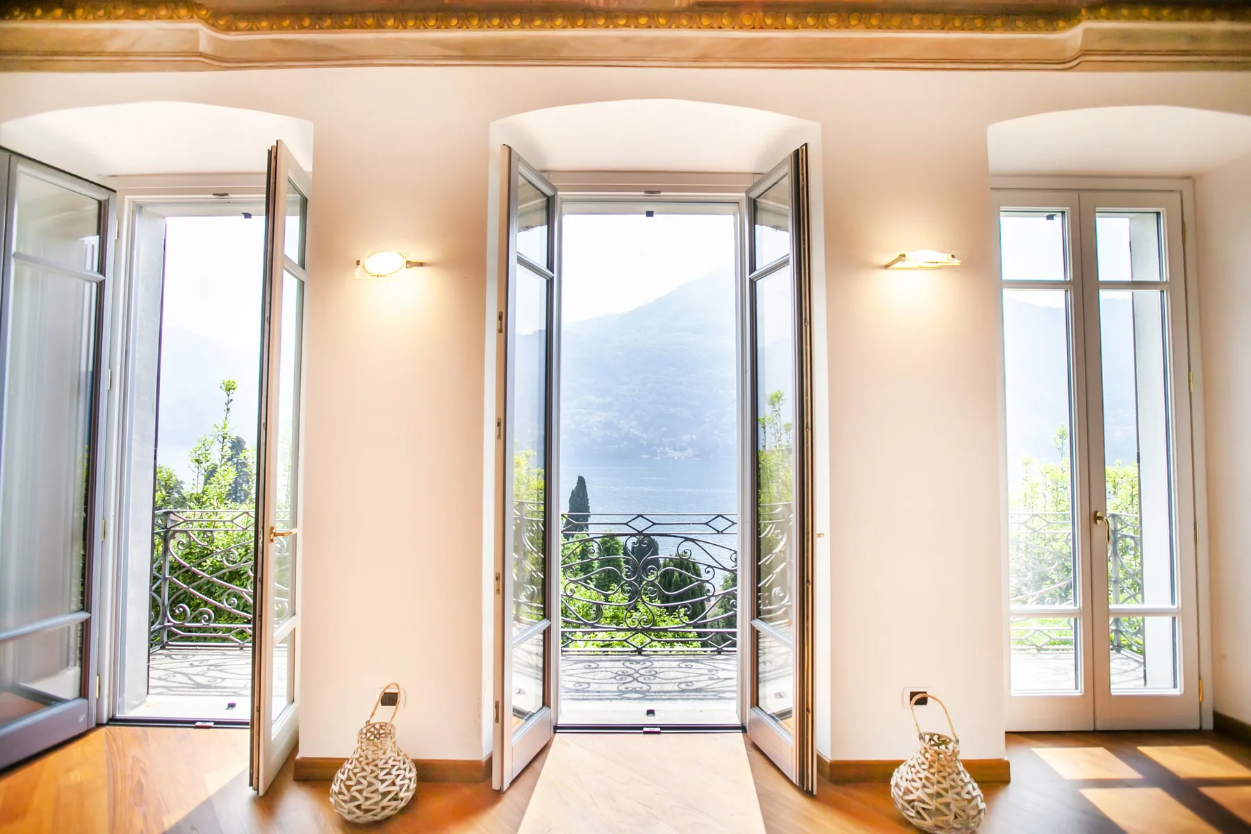 A bright room with tall windows overlooking greenery and distant hills.