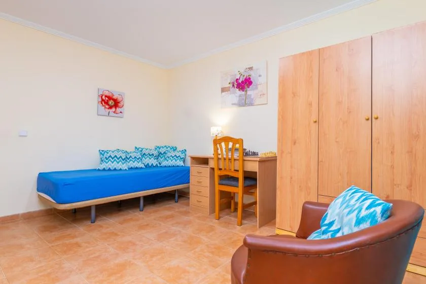 A bedroom with a single bed, a desk, and a wardrobe.
