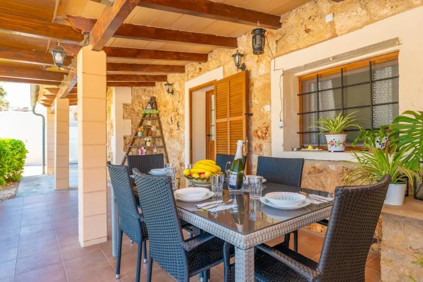 A covered outdoor dining area with a table, seating, and stone walls.
