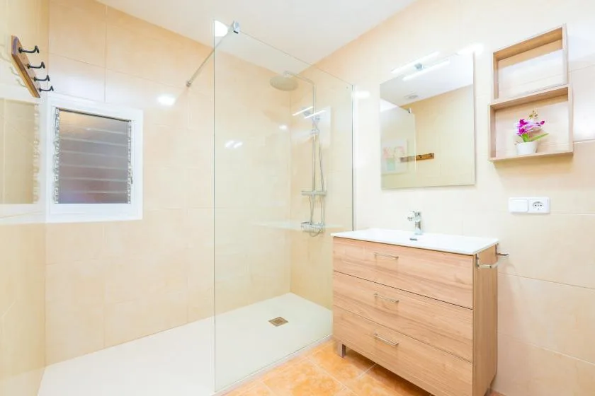 A bright bathroom with a glass shower, vanity, and mirror.