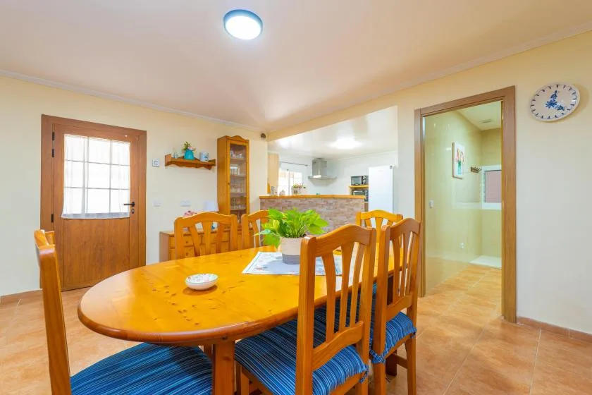 A dining area with a wooden table and chairs on a tiled floor.
