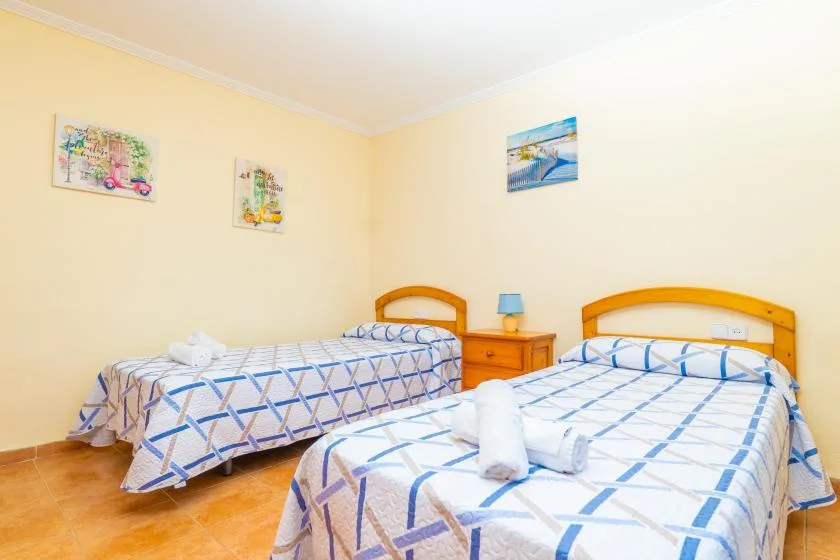 A bright bedroom with two beds dressed in blue-and-white patterned linens.