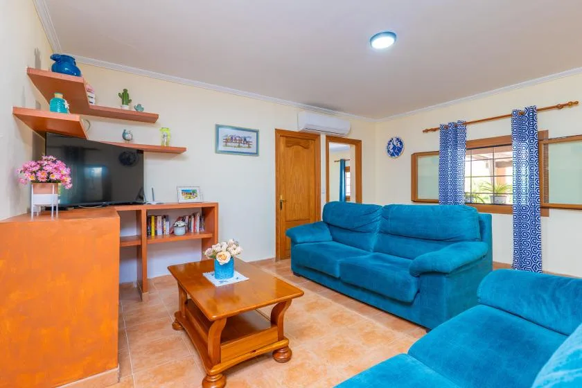 A living room with blue seating, a wooden coffee table, and a television.