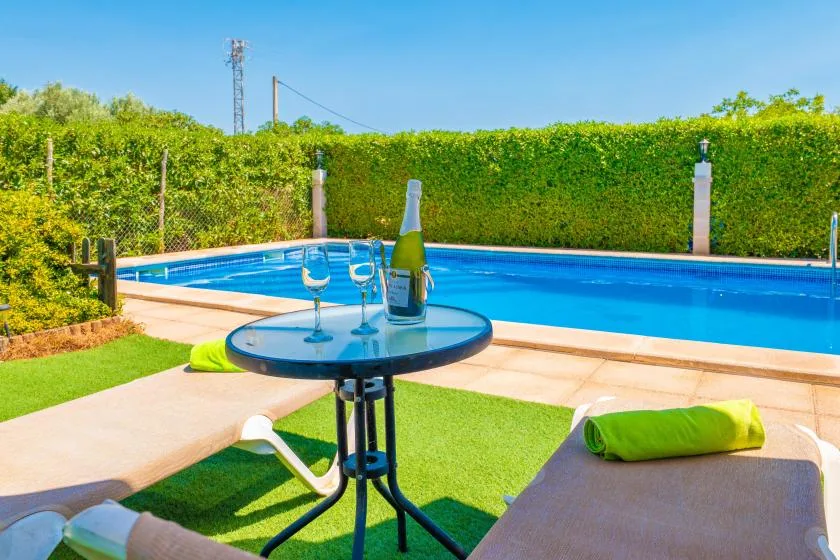 An outdoor pool beside a small round table and lounge seating.