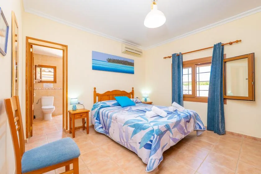 A bedroom with a double bed, bedside tables, and a window with blue curtains.