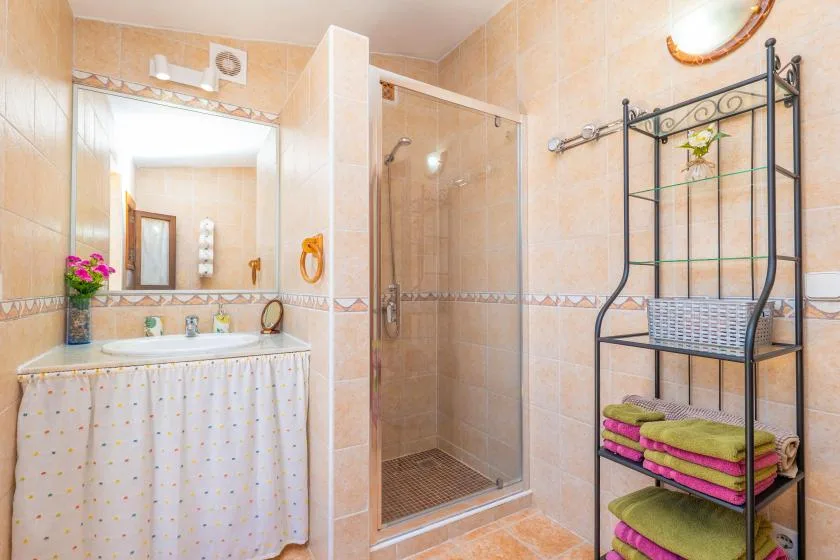 A tiled bathroom with a sink, mirror, and glass shower.