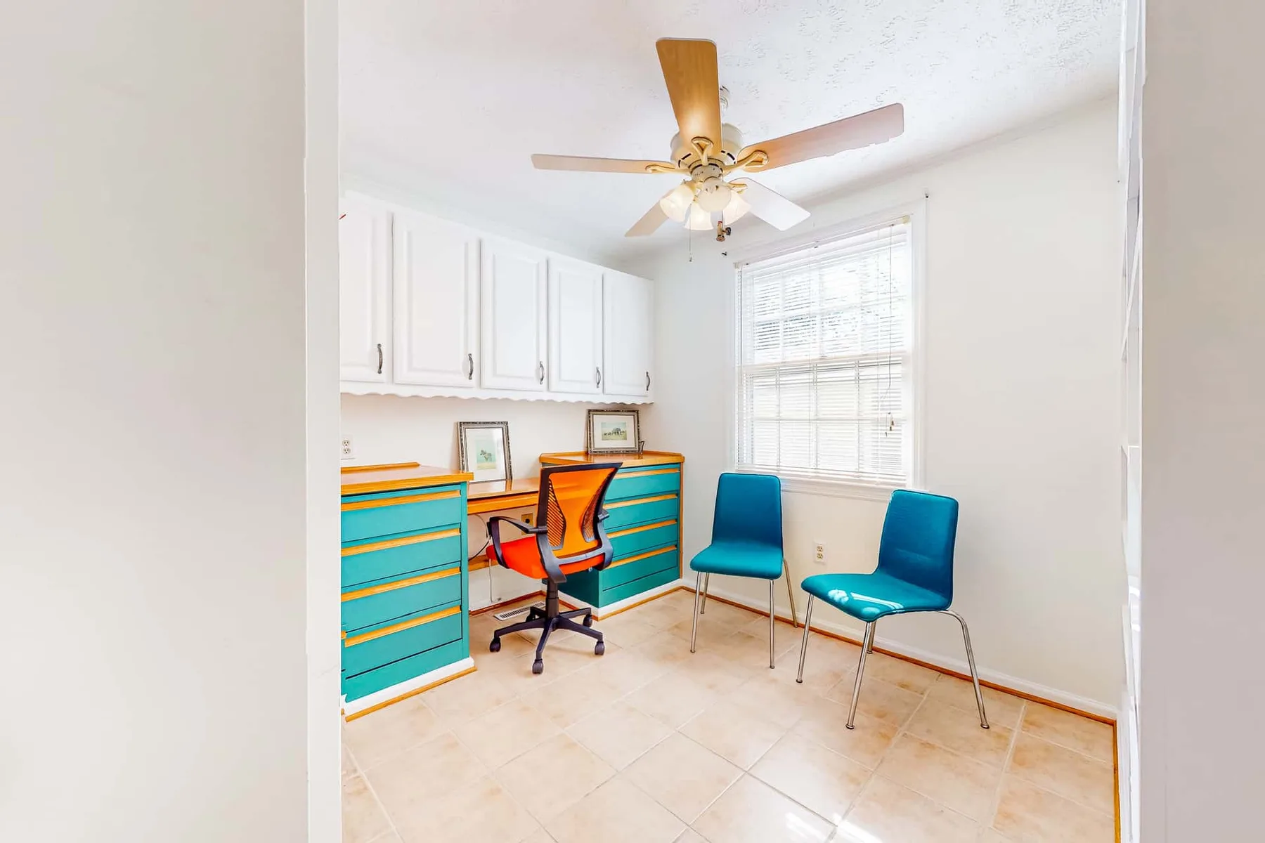 A bright study area has built-in desks, seating, and a window.