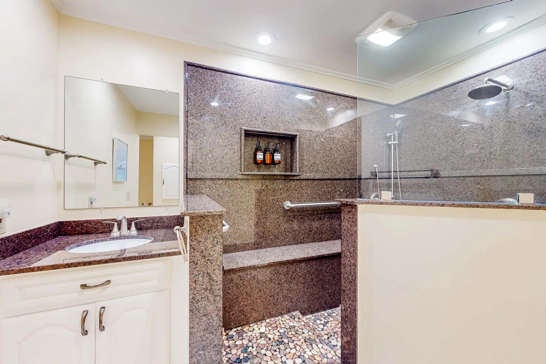 A bathroom with a vanity, mirror, and glass shower.