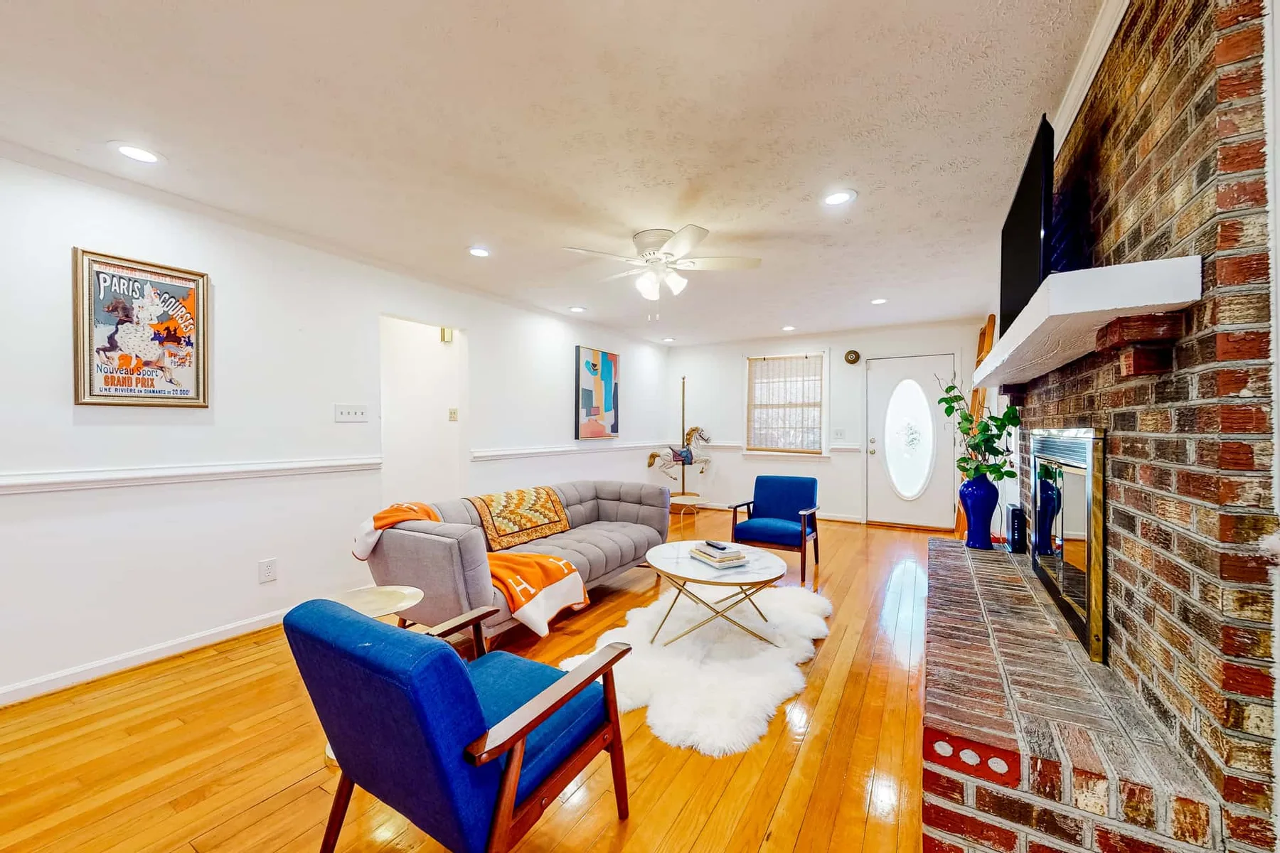 A bright living room with seating, a coffee table, and a brick fireplace.