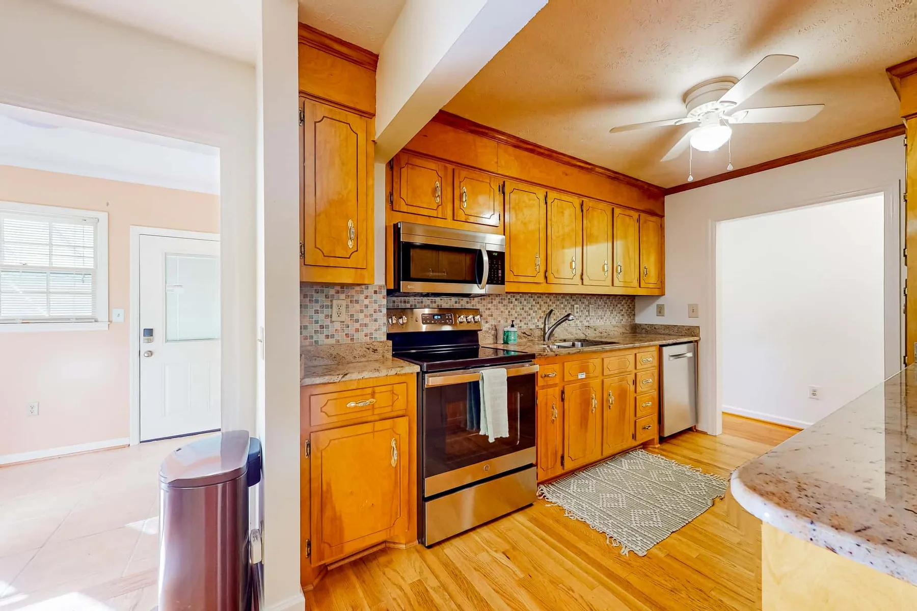 A kitchen with wooden cabinets, stainless steel appliances, and a ceiling fan.