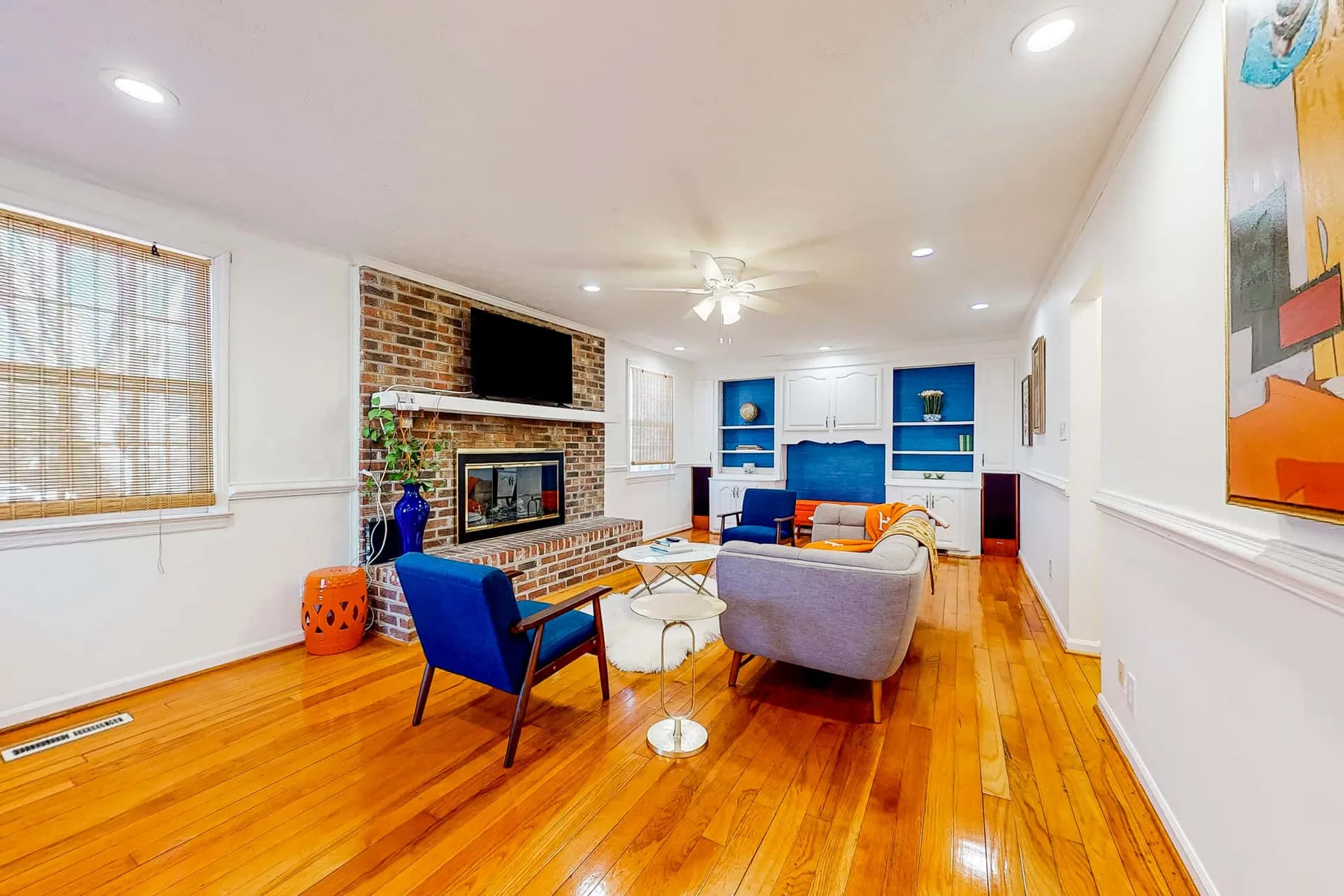 A bright living room with seating arranged around a brick fireplace.