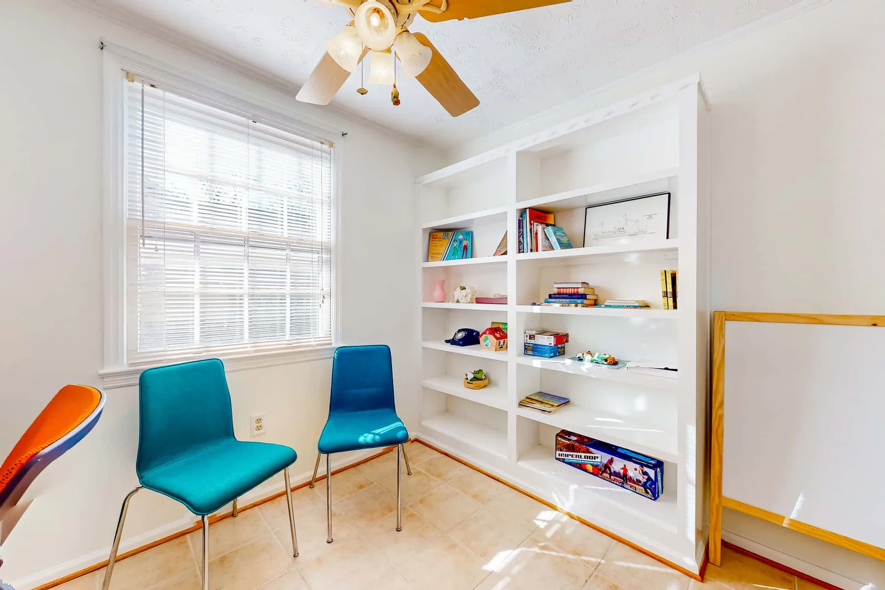 A bright room with two teal seats beside a built-in bookshelf.