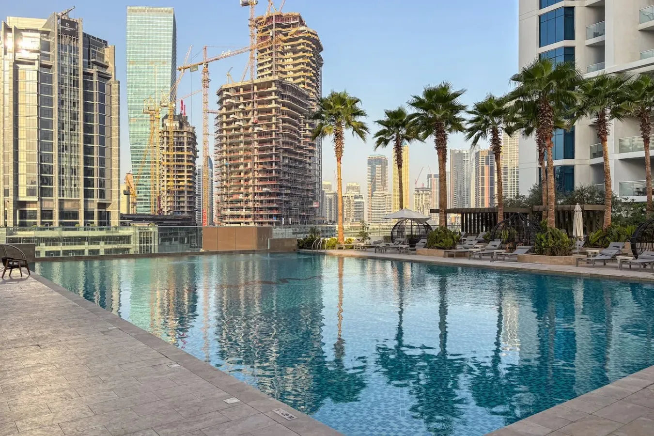 Una piscina en la azotea ofrece vistas de palmeras y edificios altos en construcción.