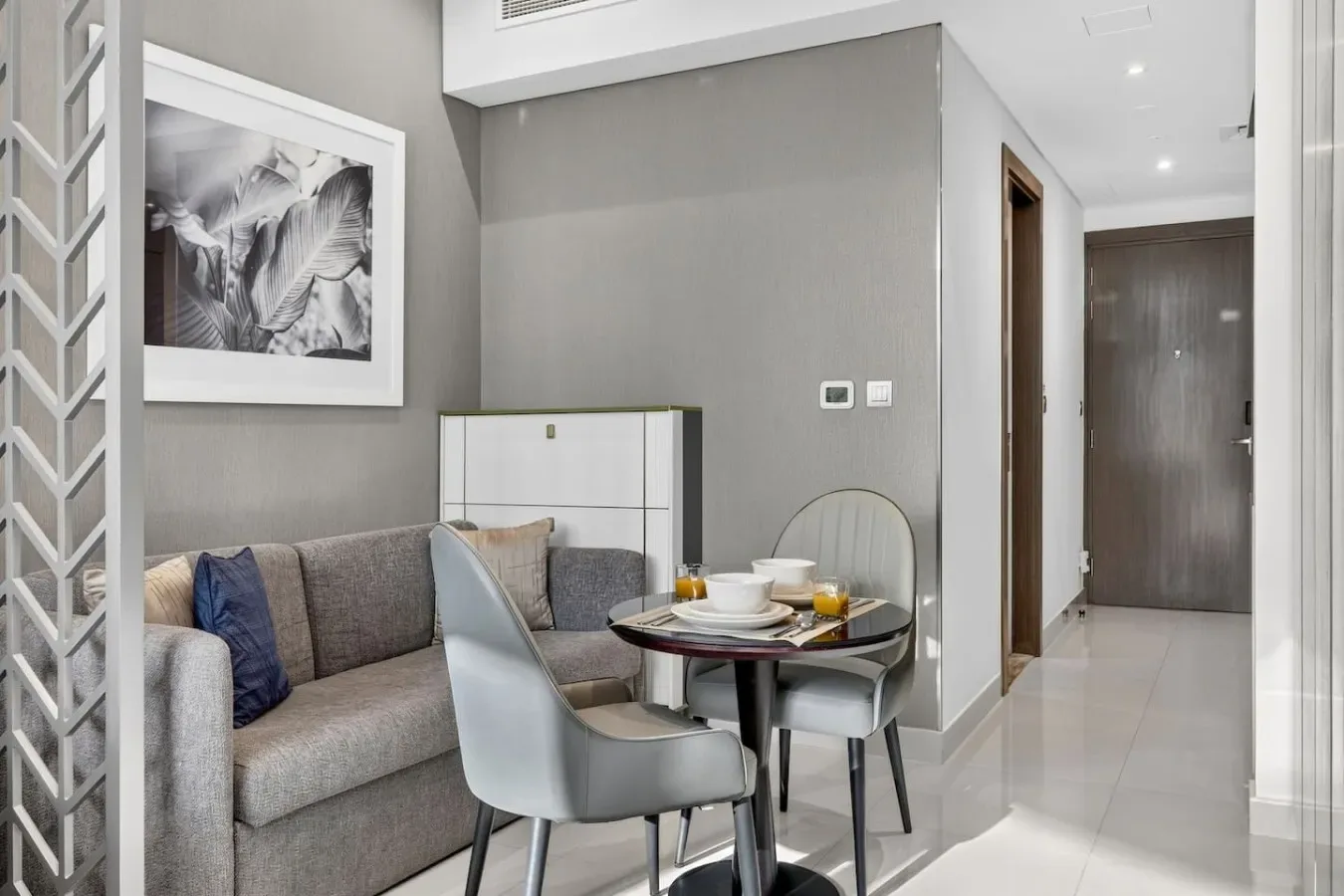 Una sala de estar y comedor moderna con un sofá gris y una mesa redonda.