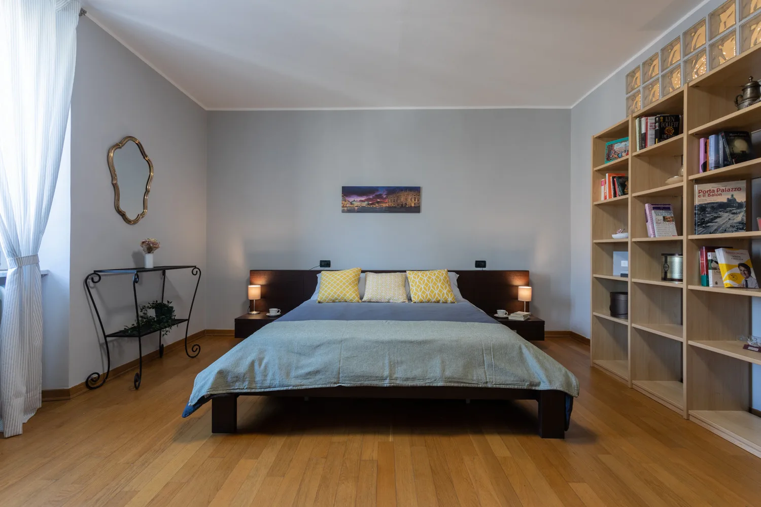 A bedroom with a bed centered between bedside tables and a tall bookshelf.