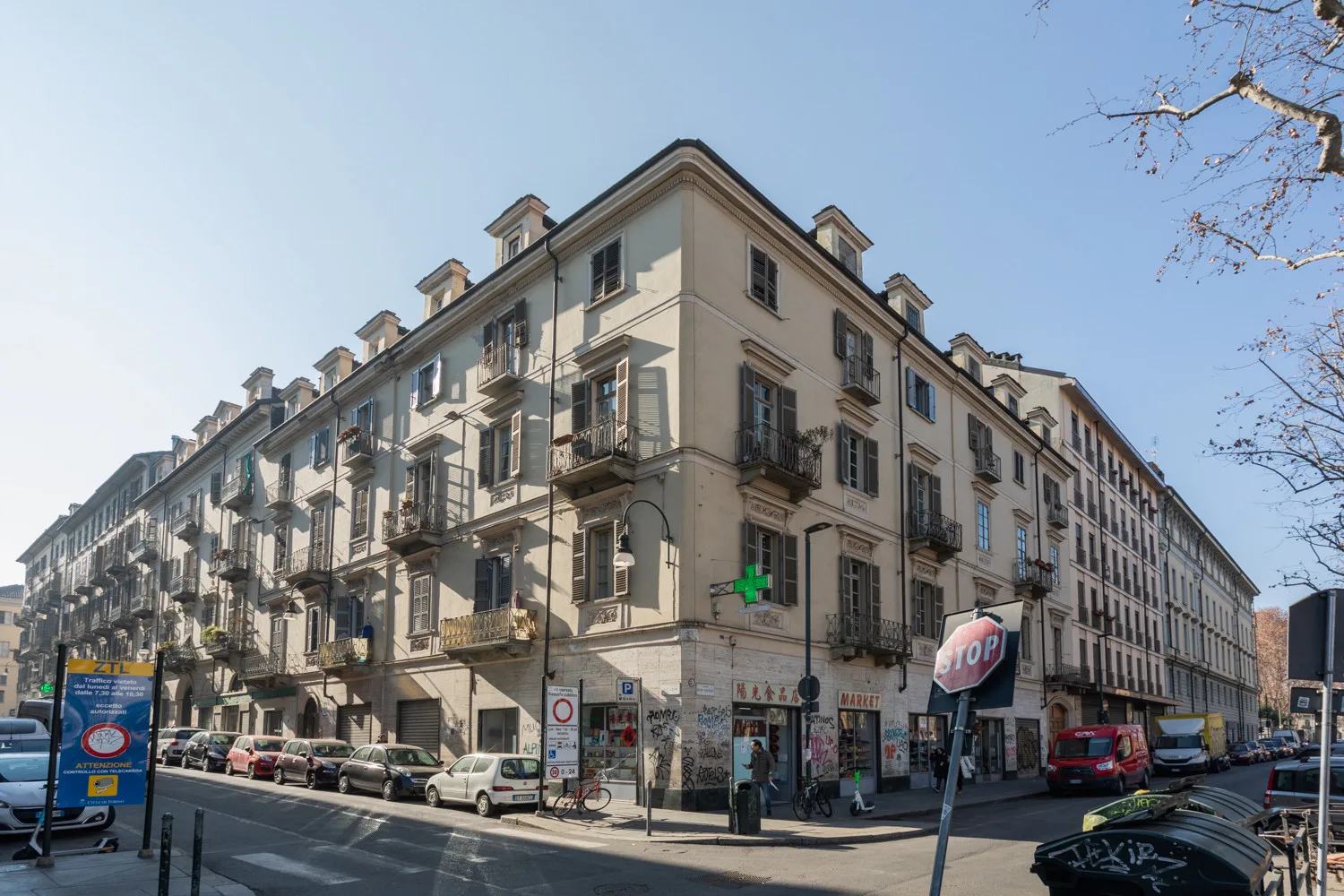 Una esquina con un edificio de varias plantas y coches estacionados.