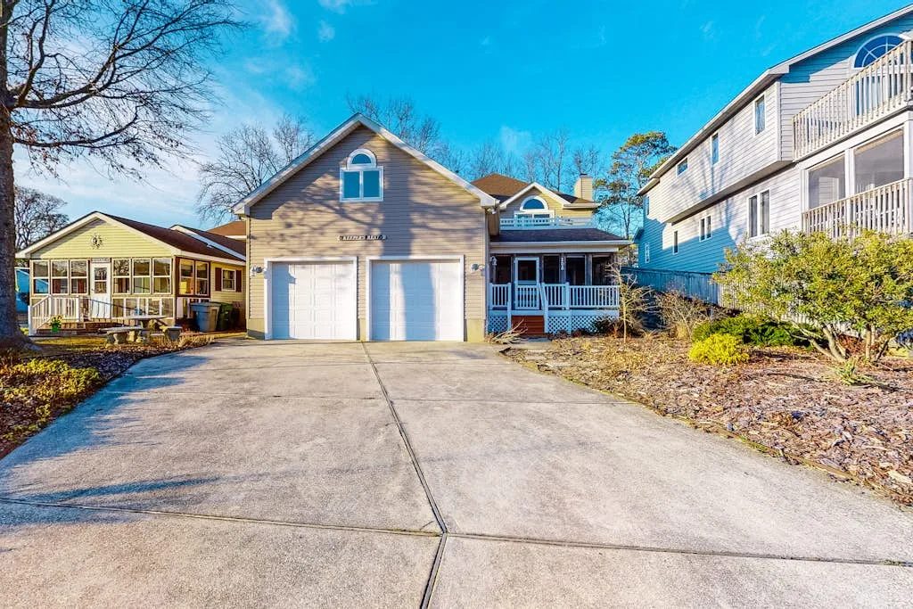 A residential building with a broad driveway, garages, and a covered porch.