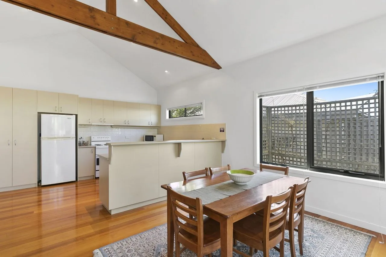 A bright kitchen and dining area with wooden seating and a large window.