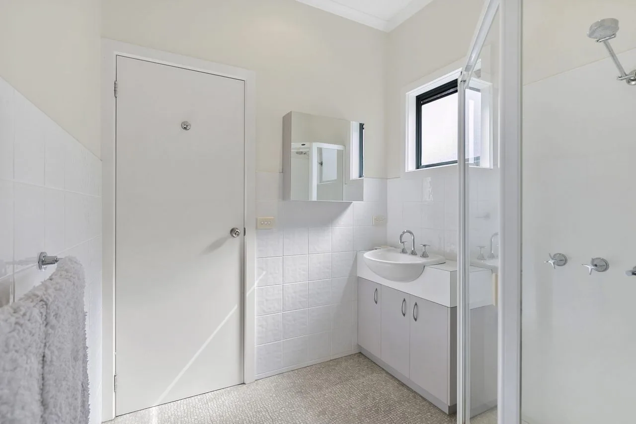 A bathroom with a vanity, mirror, and glass shower.