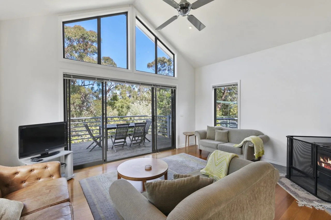 A bright living room opens onto a balcony through wide glass doors.